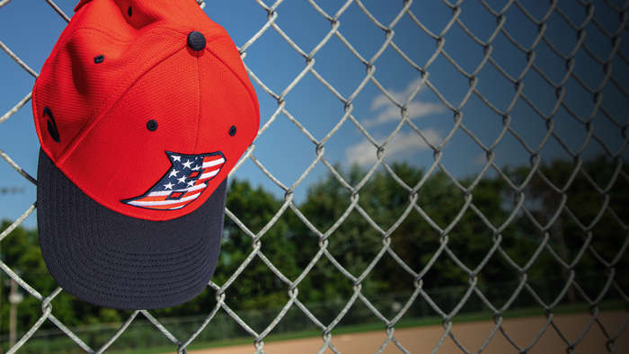 Youth Baseball hat hanging on dugout fence