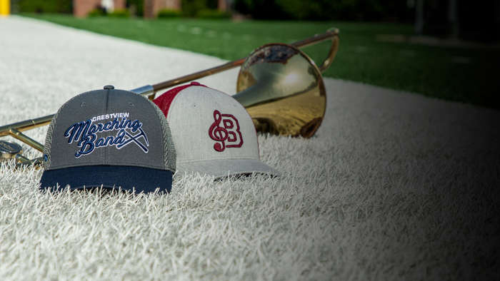 A pair of marching band hats next to an instrument