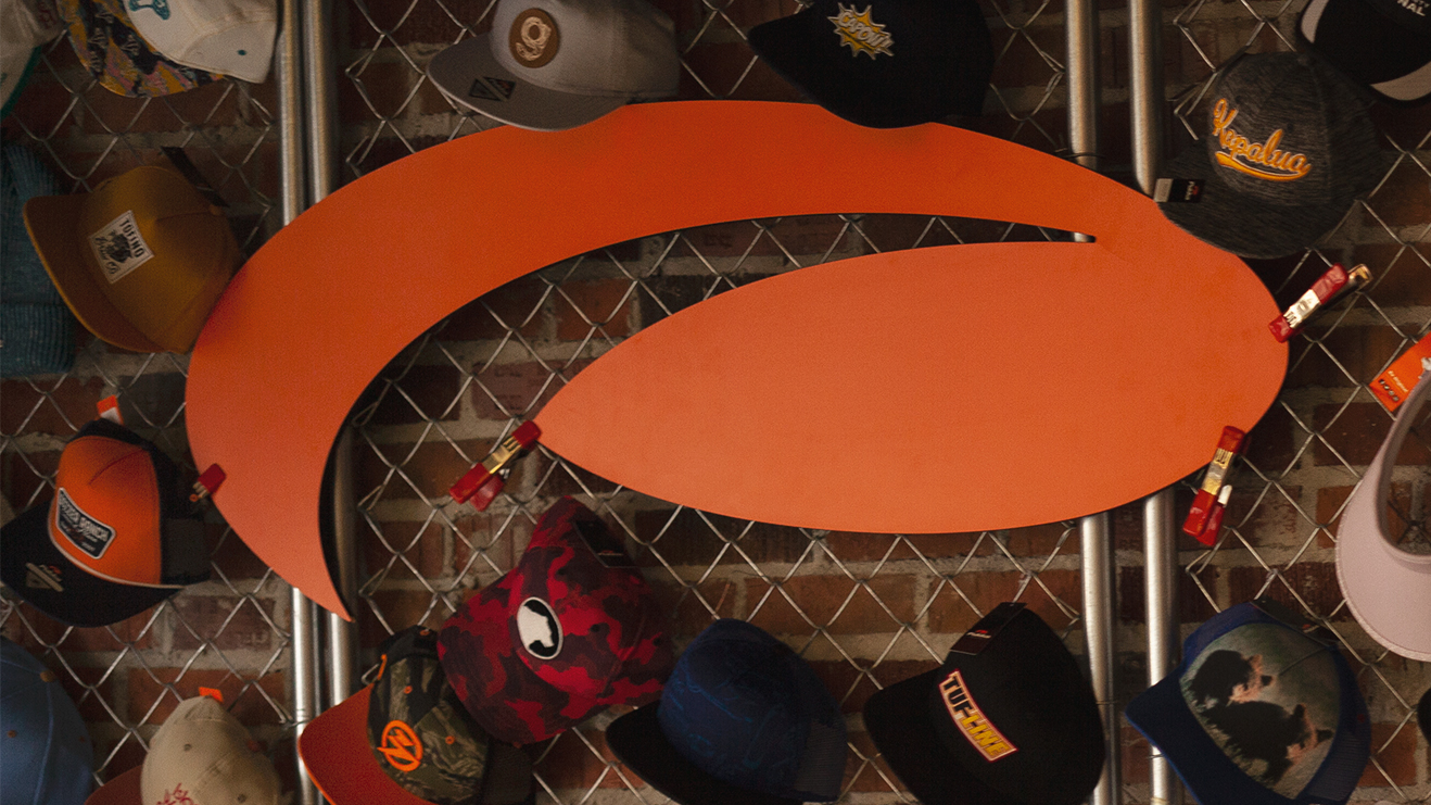 Pukka Logo on a wall surrounded by hanging hats
